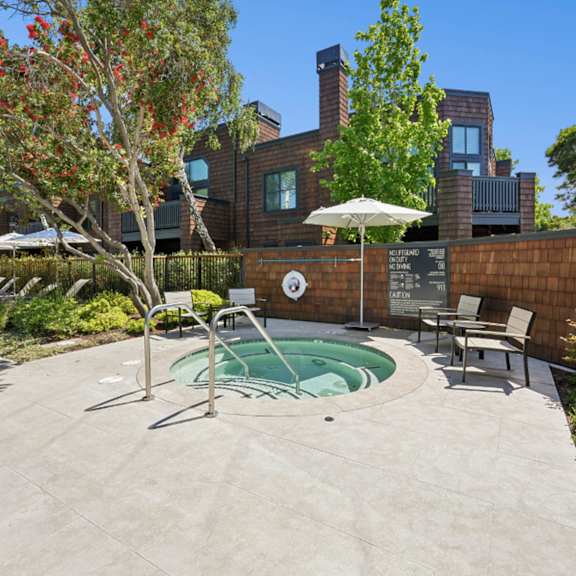 A pool area with a chair and table overlooking a body of water.