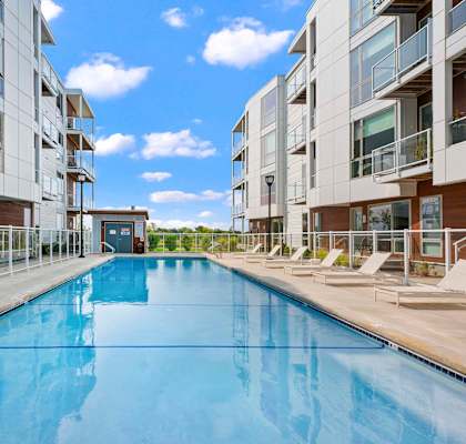 a swimming pool is between two modern apartment buildings