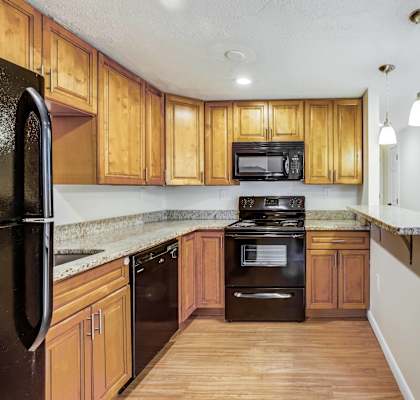 A kitchen with wooden cabinets and black appliances.