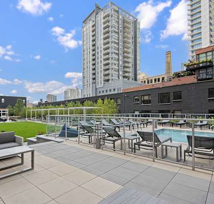 A rooftop patio with a pool and chairs.