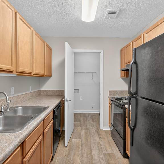 A kitchen with a black refrigerator and wooden cabinets. at Sawbranch Apartments, Summerville 29485
