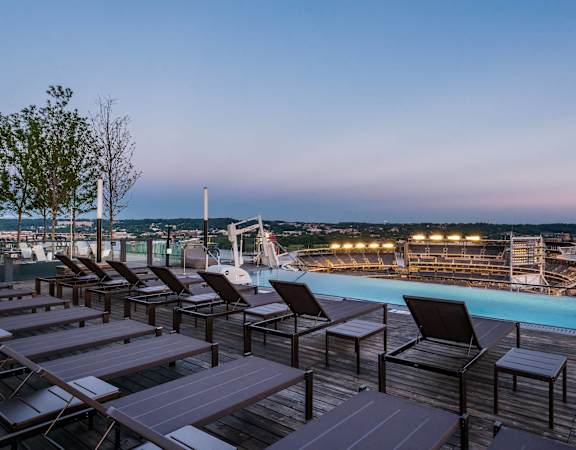 a rooftop pool with chairs and tables at night