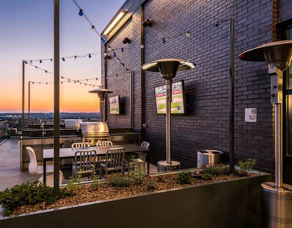 a rooftop patio with tables and chairs and a sunset