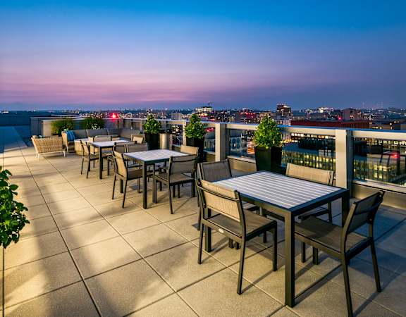 a terrace with tables and chairs overlooking a city at dusk at 220 Twentieth Street, Virginia, 22202