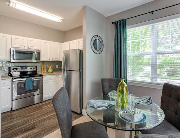 a kitchen and dining room with stainless steel appliances and a glass table