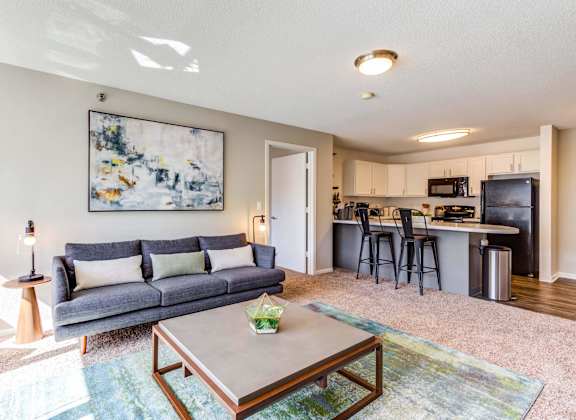 a living room with a couch coffee table and a kitchen in the background