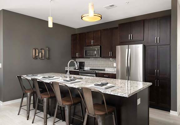 a kitchen with a marble counter top and a stainless steel refrigerator