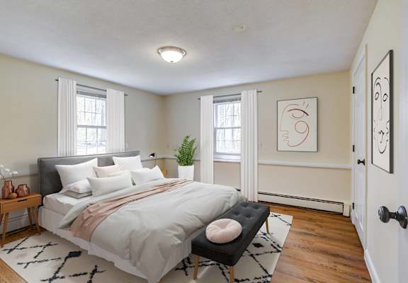 A bedroom with a large bed and a plant on the windowsill.