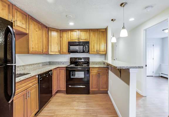 A kitchen with wooden cabinets and black appliances.