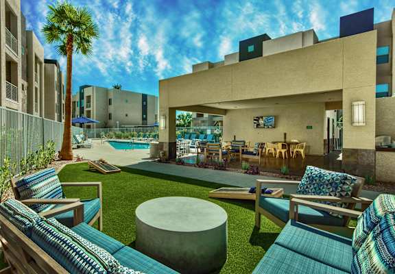 A modern outdoor seating area with a pool and palm tree. at Craft at Gilbert and Baseline Apartments, Apartments, Mesa, AZ