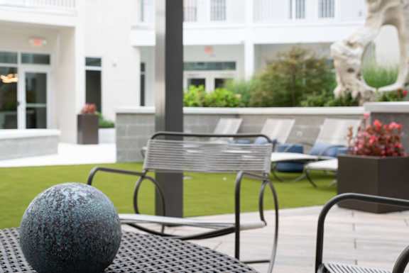 A blue ball sits on a table outside a white building.