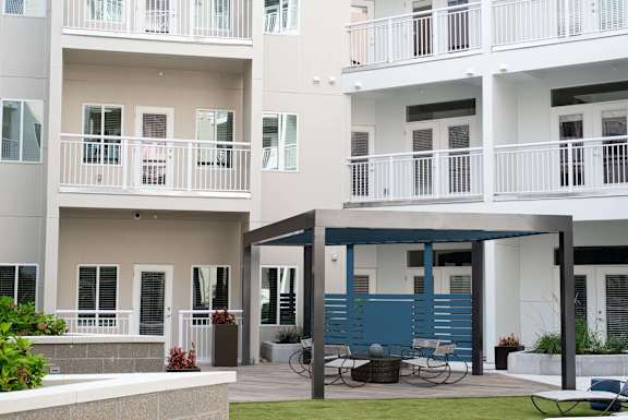 A white apartment building with a blue accent wall and a patio area with a table and chairs.