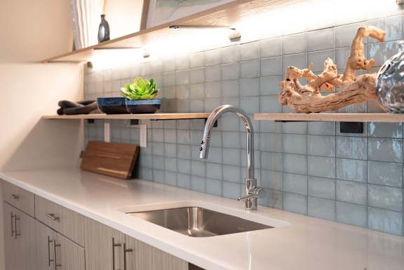 Modern kitchen sink and glossy tile backsplash in a stylish lounge at NOVI in Concord, NC.