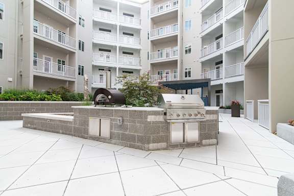 A courtyard with a stone wall and a grill in the middle.
