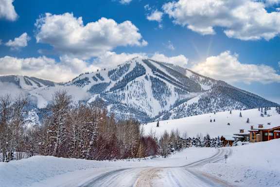 A snowy mountain landscape with a road leading towards a house at The Woods at Copper Ranch, Hailey, Idaho