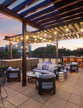 a rooftop patio with tables and chairs and a pergola at dusk