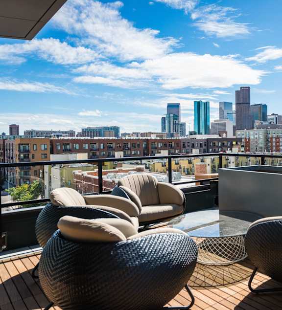 A balcony with chairs and a city skyline in the background.