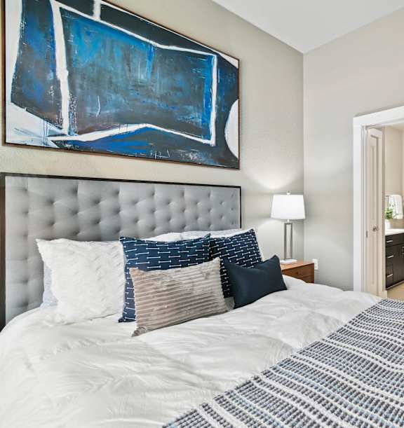 A bedroom with a large bed and a painting on the wall.