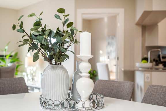 a white dining table with two white vases and a candle