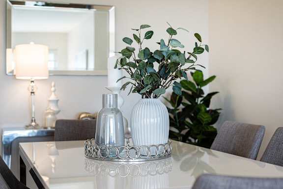 a dining room table with a white vase with flowers on it