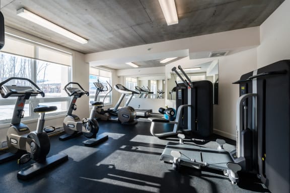 a gym with various exercise equipment on the floor and a large window