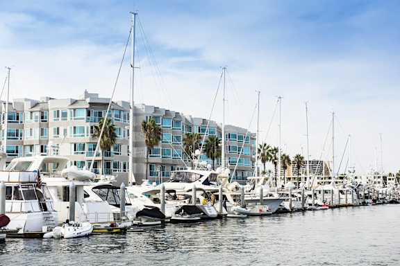 A marina with boats docked in front of a row of buildings.