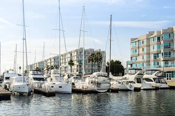 A marina with several yachts docked in front of a row of buildings.