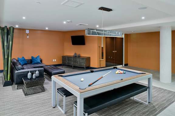 a games room with a pool table and couches