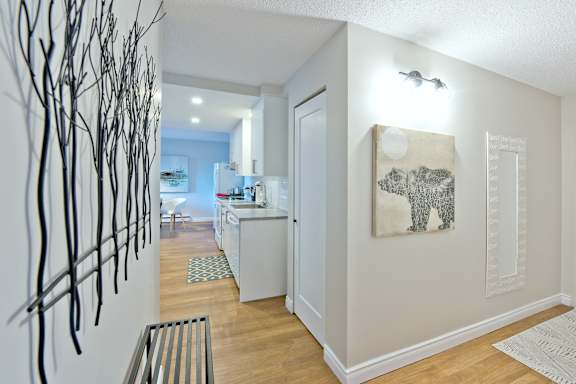 A hallway with a white wall and a painting of a tree.
