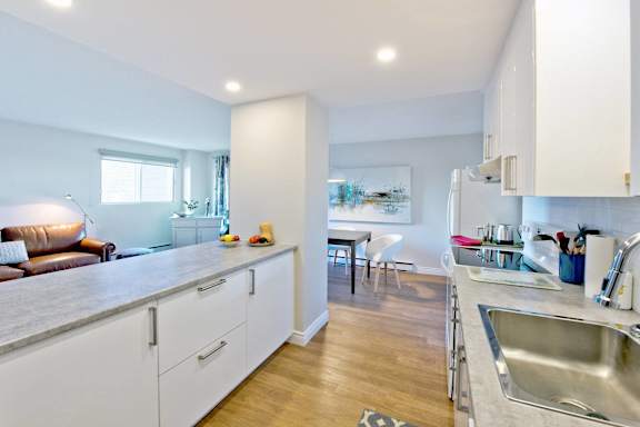 A kitchen with white cabinets and a wooden floor.