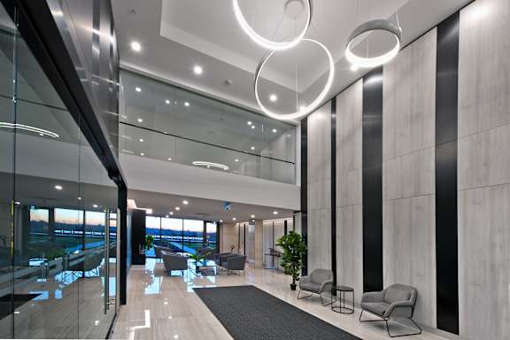 A modern office lobby with a glass wall and a view of the city.