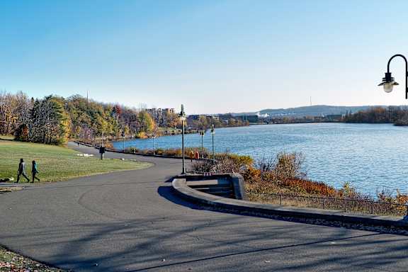 Two people walking on a path next to a body of water.