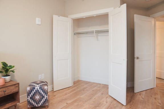an empty closet in a room with a wooden floor and white doors