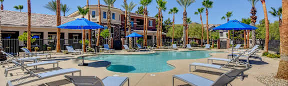 A pool surrounded by palm trees and sun loungers.