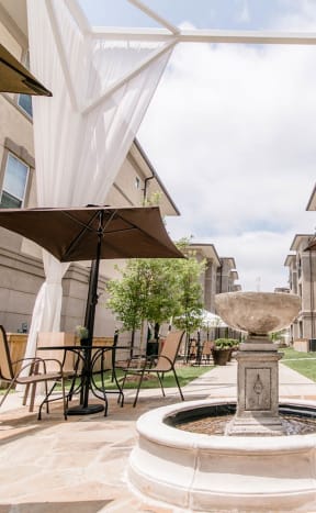 a patio with a table and chairs and an umbrella at The Villa at River Pointe, Maumelle, AR 72213