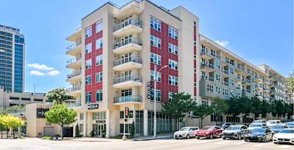 A red and beige apartment building with cars parked in front.