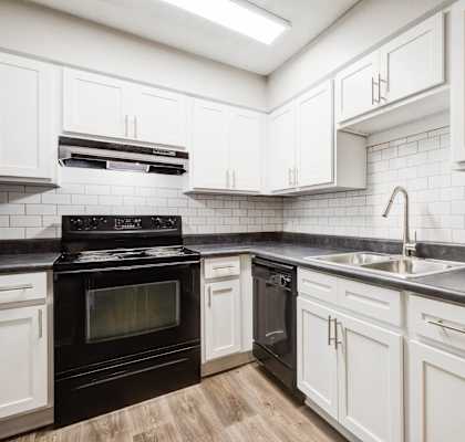 A kitchen with black and white appliances and cabinets.