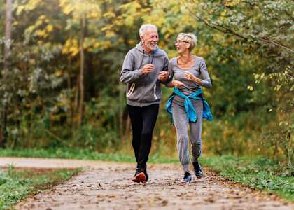 an older couple walking down a path in the woods
