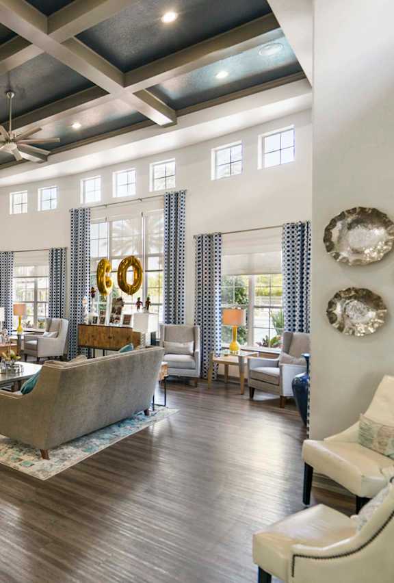 A living room with a blue couch and a glass coffee table.