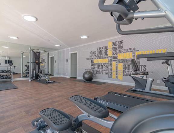 the gym is equipped with exercise machines and weights at The Flats on Addison, Sherman Oaks