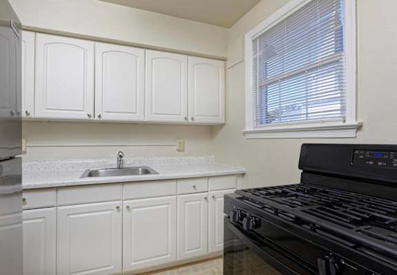 A kitchen with white cabinets and a black stove top oven.