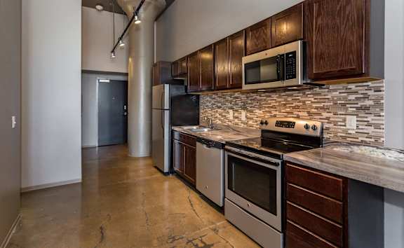 Kitchen with stainless steel appliances and wooden cabinets at Ballyard Lofts, Indigo Living