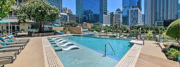 A swimming pool with a city skyline in the background.