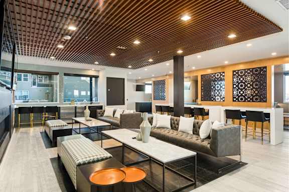 A modern living room with a wooden ceiling and a black and white sofa.