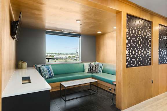 A room with a green couch and a television on the wall.