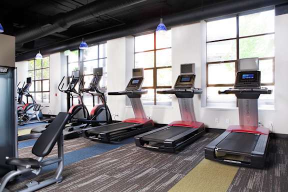 A gym with a variety of equipment including treadmills, weights, and exercise balls.
