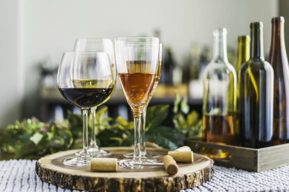 two glasses of wine on a table with bottles of wine