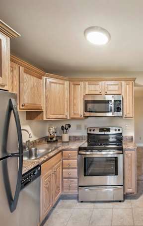 A kitchen with wooden cabinets and stainless steel appliances at Rivercrest Apartments, Piscataway , NJ
