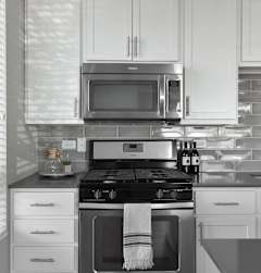 A modern kitchen with white cabinets and a black stove top.