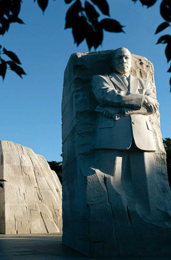 a statue of a man in a suit is standing in front of two large rocks